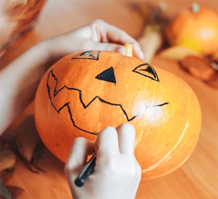 A child decorating a pumpkin for Halloween